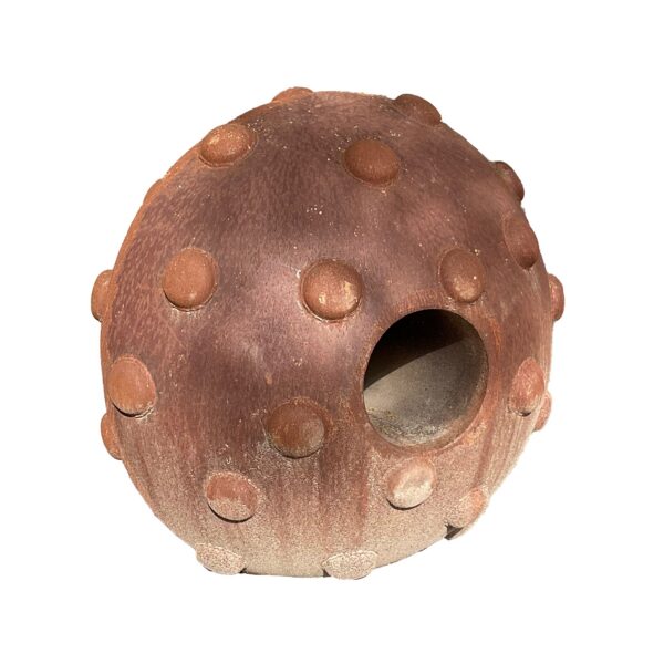 Rounded rusted steel sculpture with a domed, dimpled surface and a large circular opening on one side