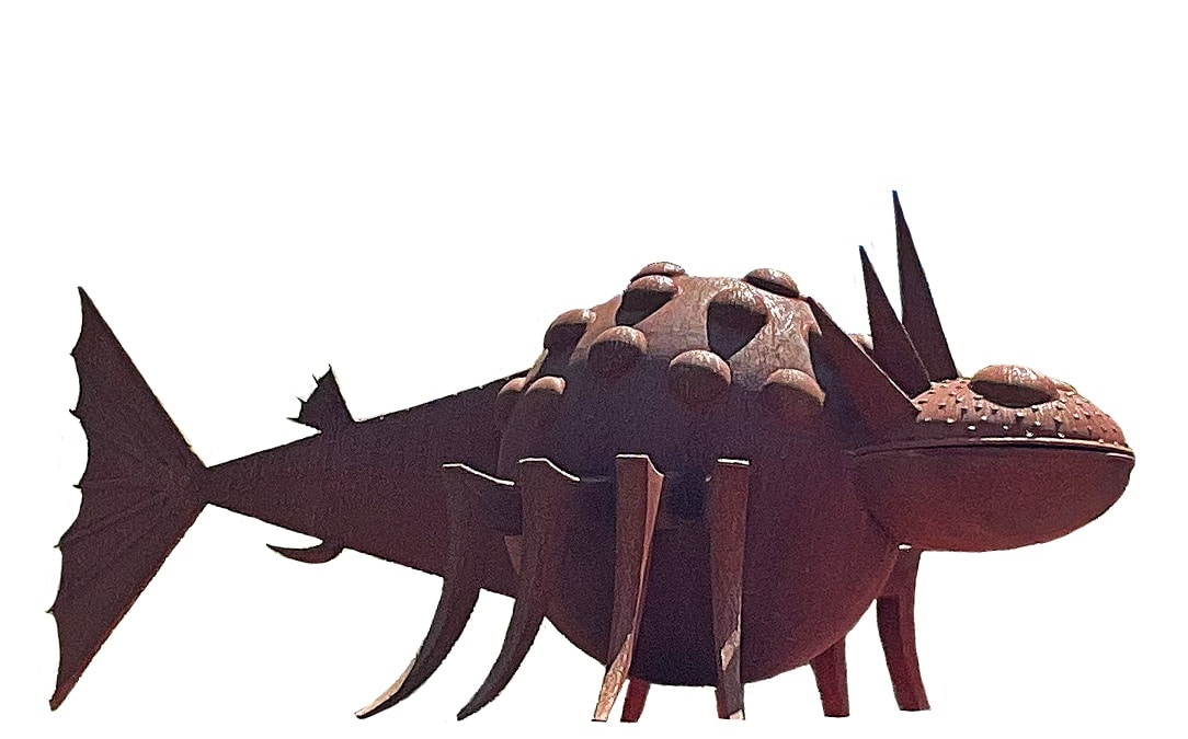 Rusted steel fish-shaped sculpture with a spiked bulbous head, dotted texture, fin-like legs, and a fan-shaped tail