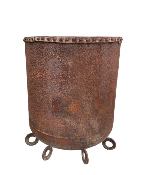 Tall round up-cycled metal planter with a heavily textured rust surface, riveted rim band, and four ring-shaped feet