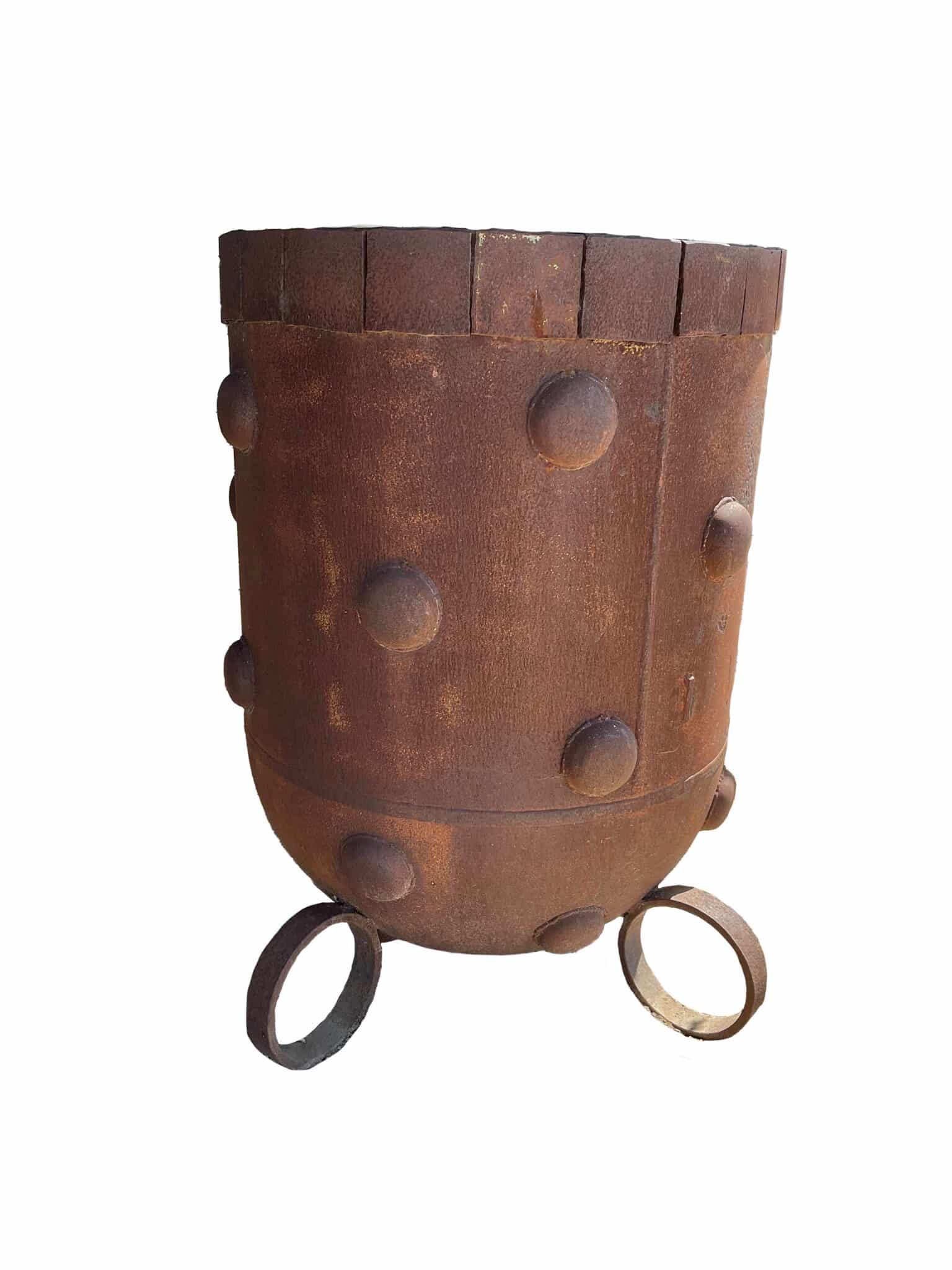Tall up-cycled metal planter with a rounded base, rust patina, decorative raised dome studs, and ring-shaped feet