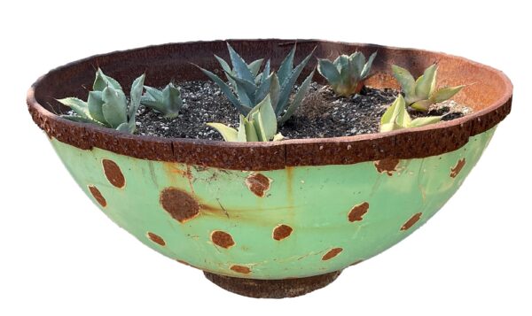 Deep, wide up-cycled metal bowl planter with a green and rust spotted patina, planted with several small agave pups