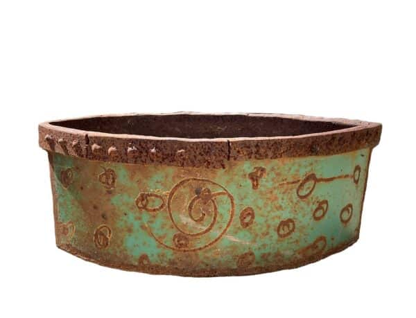 Short, wide round up-cycled metal planter with a turquoise patina, riveted rim, and an etched swirl design